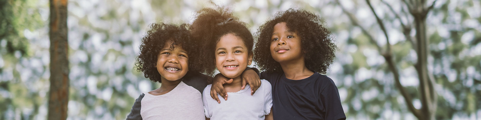 group of three African American children smiling with arms around each other