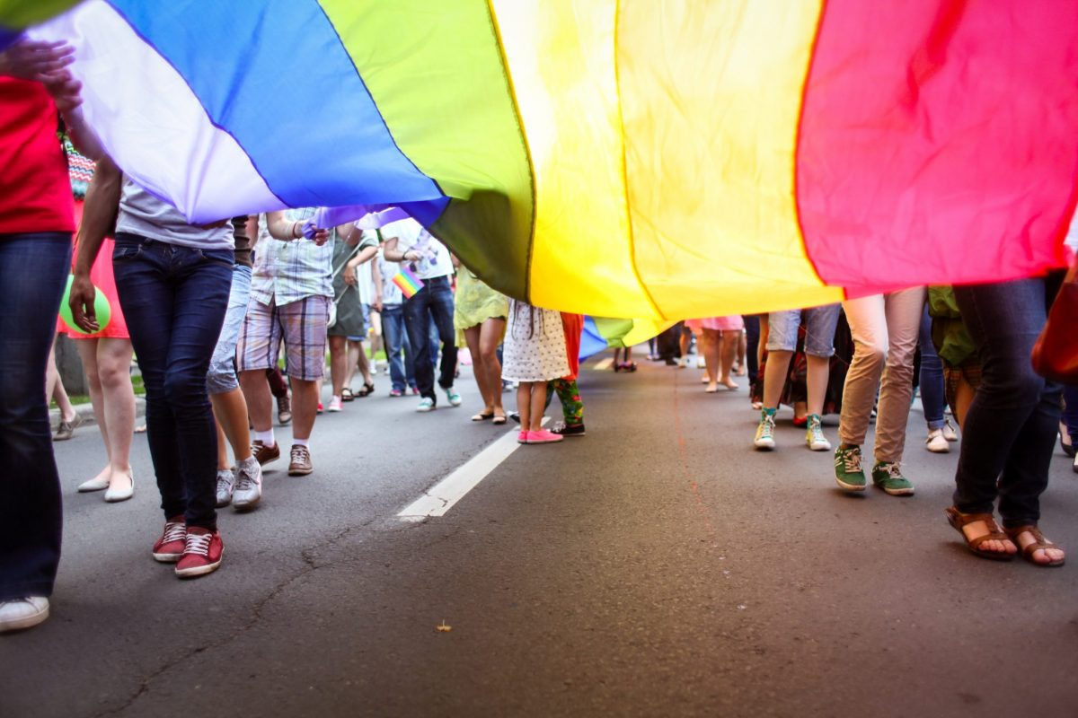 people walking with a large rainbow flag
